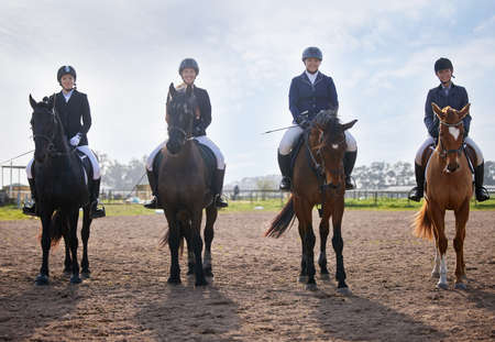 They share a love of horse riding. Full length shot of a group of attractive young female jockeys riding their horses out on the farm.の写真素材