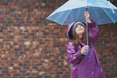 Its raining, its pouring.... Cropped shot of a little girl standing under an umbrella outside.の写真素材