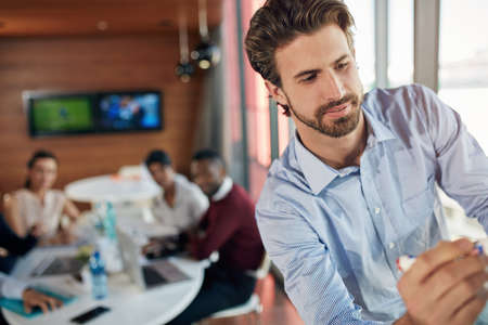 Going through the facts and figures. Cropped shot of a young businessman giving a presentation.の写真素材