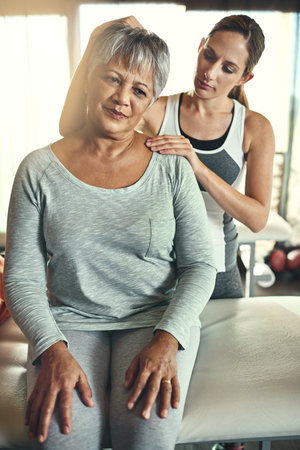 Allow me to take the pressure of. Shot of a senior woman being treated by a physiotherapist.の写真素材