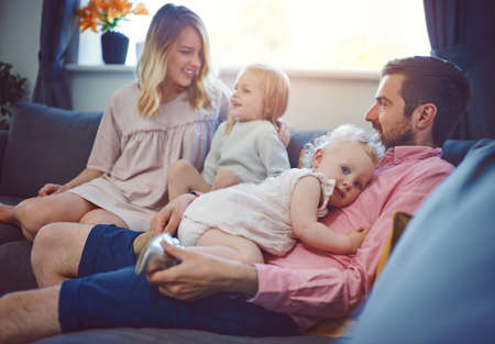 Make time for those you love. Shot of an adorable young family of four relaxing together on the sofa at home.の写真素材