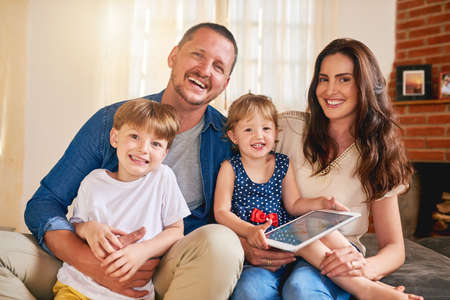 The happy home is made with a familys love. Portrait of a happy young family of four relaxing...