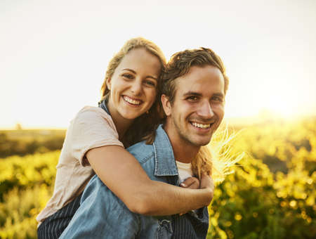 We always have fun outside in nature. Shot of a young couple walking through their farm while having...