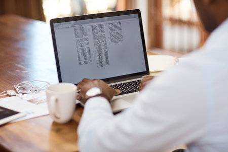 Working on his latest draft. Rearview shot of an unrecognizable young businessman working on his...