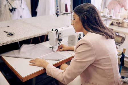 You can depend on her to deliver exceptional work. Shot of a seamstress using a sewing machine while...