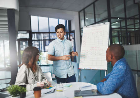 Let me put your mind at ease. Shot of a young businessman using a whiteboard to give a presentation...