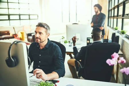 Hes something of a creative genius. Cropped shot of a mature businessman working on his computer in the office.の写真素材
