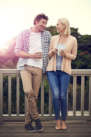 I fall in love with you a little every day. Shot of a happy couple drinking coffee on their balcony together.の写真素材