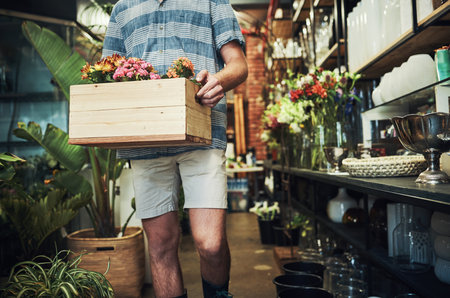 Fresh and wonderful flowers coming right up. Cropped shot of an unrecognizable florist holding a crate full of flowers inside a plant nursery.の写真素材