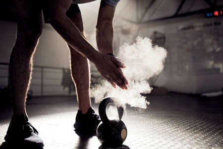 Dont go through life obsessing about what might have been. Shot of an unrecognisable man rubbing sports chalk on his hands while exercising with a kettlebell in a gym.の写真素材