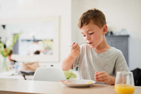 Starting the day the nutritional way. Shot of an adorable little boy having breakfast at home.の写真素材