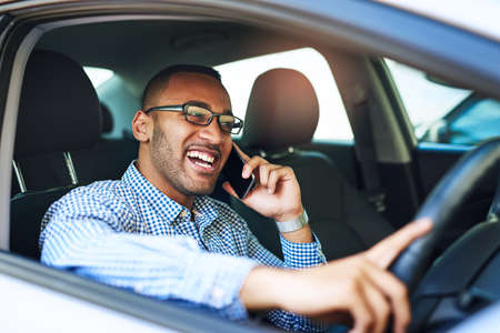 Im just around the block. Cropped shot of a young businessman talking on a cellphone while driving a...