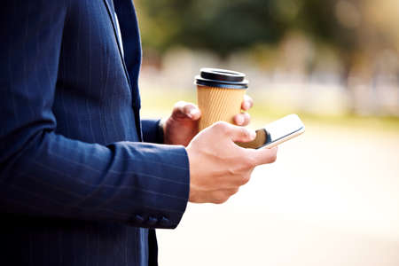 ..... Shot of a businessman using his smartphone while drinking coffee.の写真素材