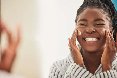 My secret is a good face cream. Cropped shot of a beautiful young woman applying mascara.の写真素材