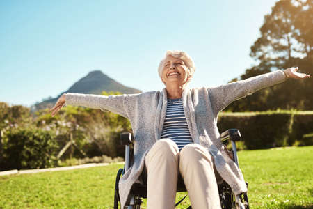 Dont take away their freedom. Shot of a senior woman enjoying the outdoors while sitting in her wheelchair.の写真素材