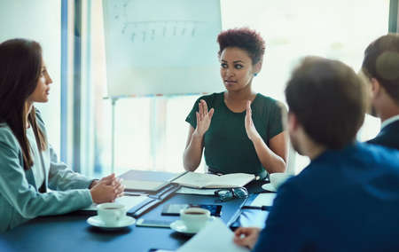 Outlining new ideas in the boardroom. Shot of a young executive talking during a meeting with...