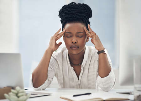 I dont need this headache right now. Shot of a young businesswoman experiencing a headache while at work.の写真素材