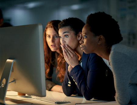 What just happened.... Cropped shot of a group of colleagues looking shocked while working late in an office.の写真素材