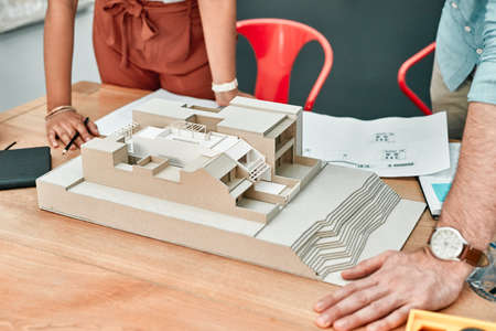 Designing their dreams is part of the job. Closeup shot of two architects working together on a scale model of a building in an office.の写真素材