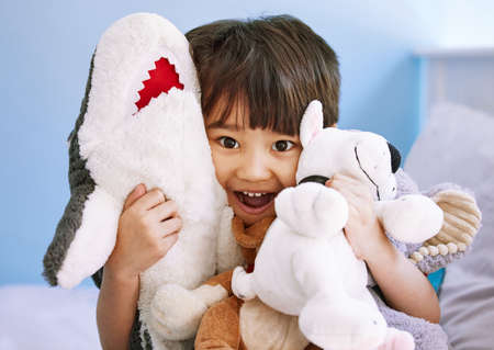 These are all my cuddly friends. Portrait of an adorable little boy playing with his stuffed toys at...