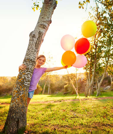 Balloons are like bubbles of magic. Portrait of a little girl playing with a bunch of balloons outdoors.の写真素材