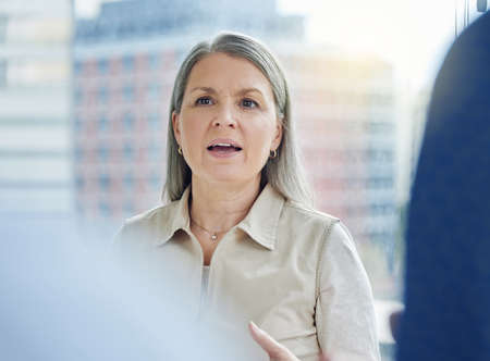 Addressing her employees. Cropped shot of an attractive mature businesswoman addressing her colleagues while standing on the office balcony.の写真素材