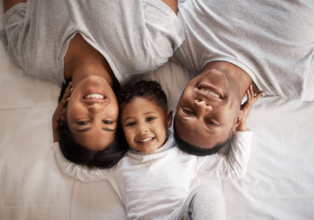 I have the best parents. High angle shot of a young couple lying in bed and bonding with their son...