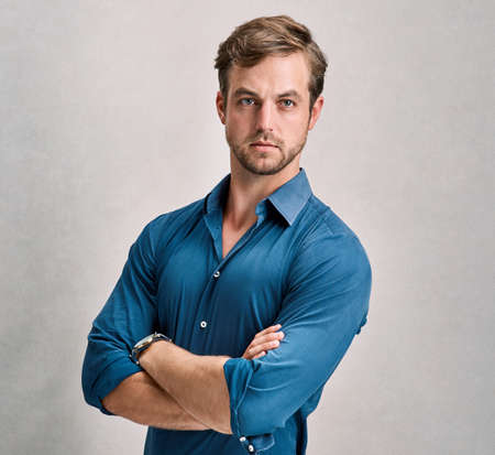 Confident and casual. Studio portrait of a handsome young man standing with his arms crossed.の写真素材