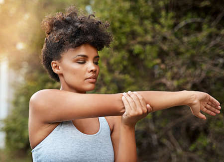 Go further than what they say you can. Shot of a young woman stretching outside before her run.の写真素材