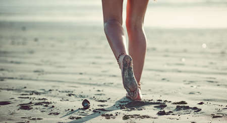 Letting her feet guide her. Cropped shot of an unrecognizable woman walking on the beach.の写真素材
