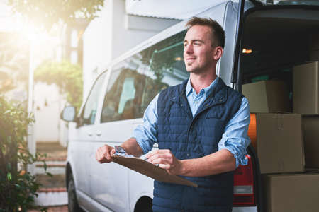 Getting his deliveries out. Shot of a courier checking his deliveries in his van.の写真素材