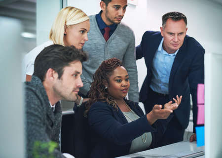 Getting feedback from her team. Cropped shot of a group of corporate colleagues gathered around a...