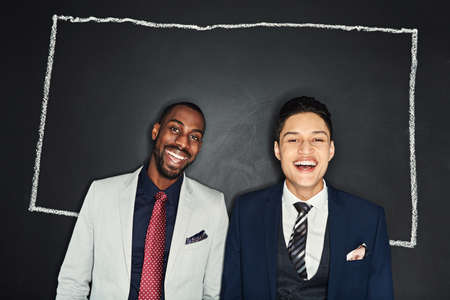 The successful are always thinking outside the box. Portrait of two young businessmen standing against a chalk illustration of a box on a dark background.の写真素材