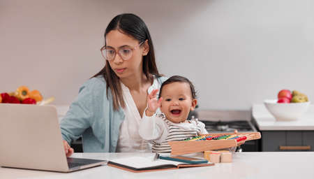 Building a life for the two of us. Shot of a young mother working from home while holding her baby.の写真素材