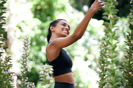 I cant not take a selfie out here. Shot of an attractive young woman standing alone and using a...