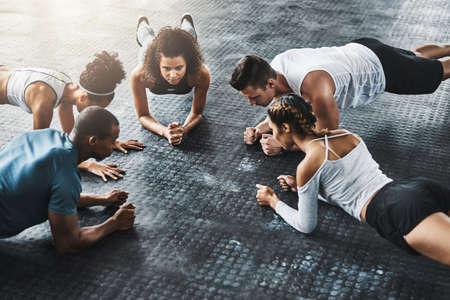 Planking - so simple, so effective. Shot of a group of young people doing planks together during...