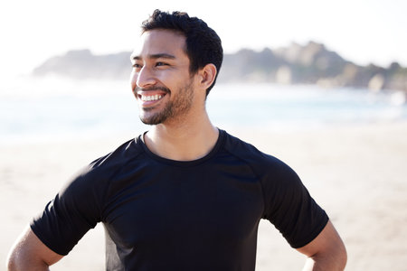 Nothing like a little exercise to lift your spirits. Cropped shot of a handsome young male athlete looking thoughtful while working out on the beach.の写真素材
