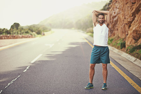 Im ready to run. Are you. Portrait of a young man stretching before going for a run.の写真素材