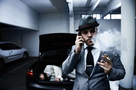 Letting his employers know the job is done. An arrogant mobster smoking a cigar and informing his employer that the abduction was successful.の写真素材