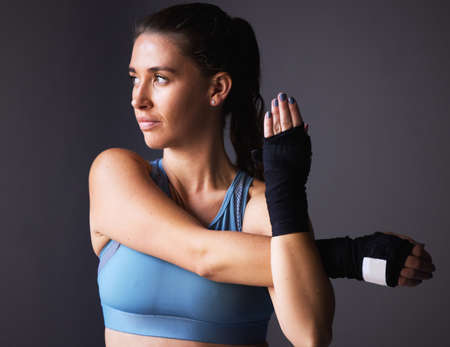Its all in the mind. Shot of a young woman stretching her arms against a grey background.の写真素材