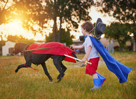 Ready to fight crime. Shot of a little boy and his dog wearing capes while playing outside.の写真素材
