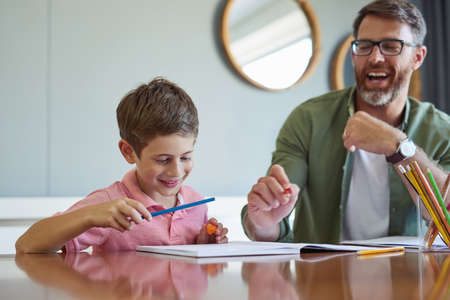 Dad knows how to turn learning into a fun experience. Shot of a father helping his little son with his homework.の写真素材