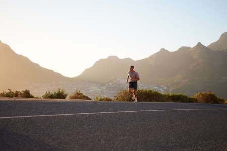 A morning jog to clear the head. Shot of a young man running alone outside.の写真素材