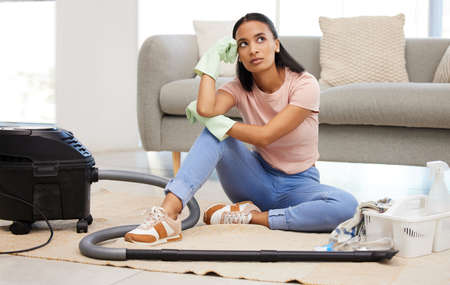 Do I have to do all this cleaning. Shot of a young woman sitting on the floor looking contemplative at home.の写真素材