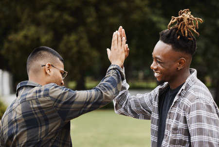 Put it up top. Shot of two young men giving each other a high five on campus.の写真素材