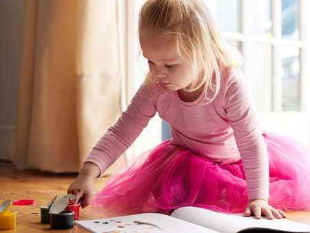 I like all things pink and colourful. Shot of a little girl doing a finger painting at home.の写真素材