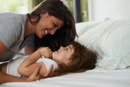 Guess who Mommy loves the most. Shot of a mother and her little daughter bonding together at home.の写真素材
