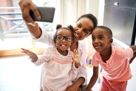 Capturing happy moments. Cropped shot of an affectionate young family taking selfies at home.の写真素材