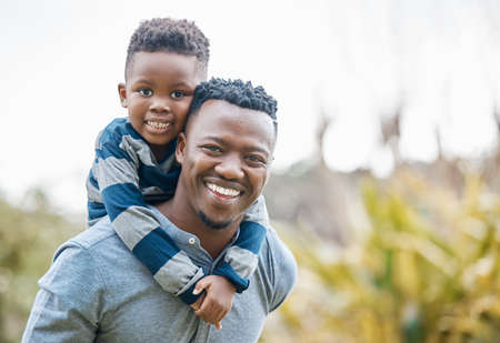 Hes my little champ. Shot of a young father bonding with his son and giving him a piggyback ride in the garden.の写真素材