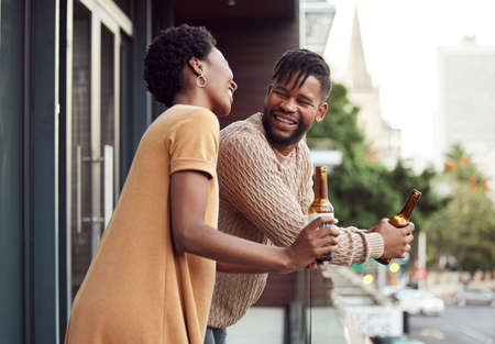 Love makes every moment extra special. Shot of an affectionate your couple drinking beer while bonding on a balcony outdoors.の写真素材